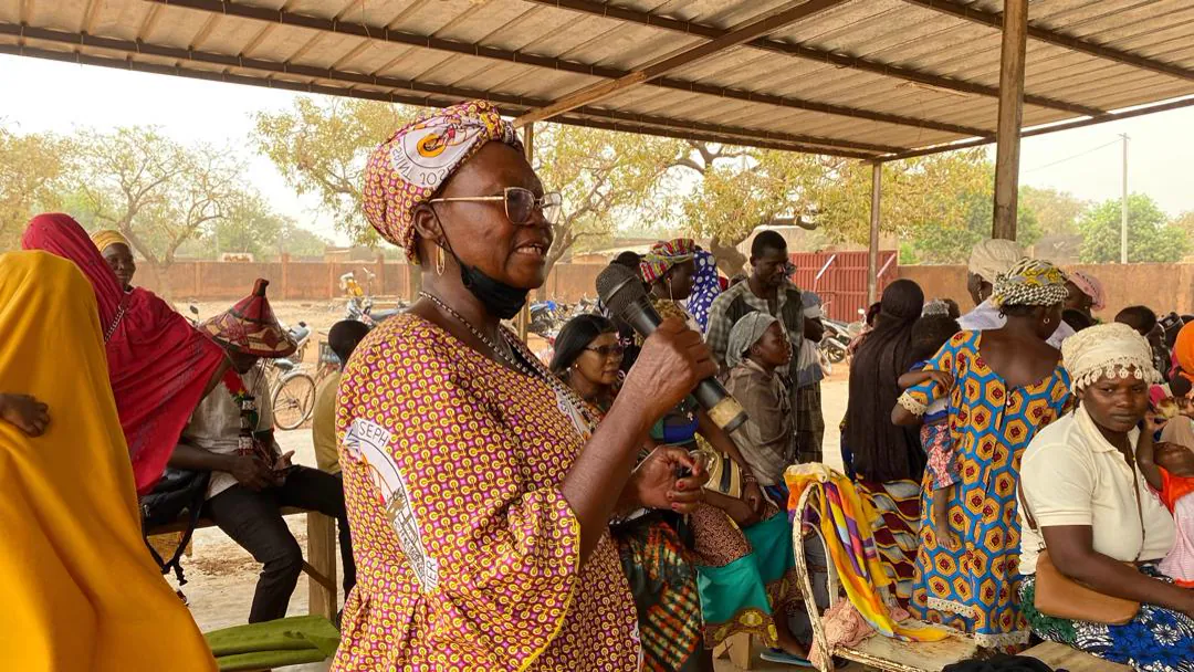 Une intervenante parle au micro devant un groupe de femmes assises.